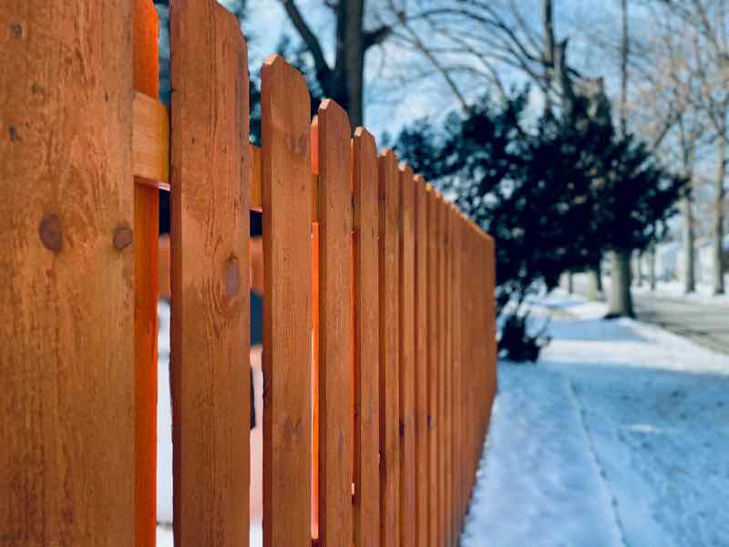 Wood shadowbox fence beside a snowy sidewalk
